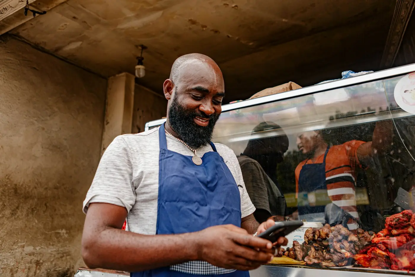 A butcher checking his phone at his counter