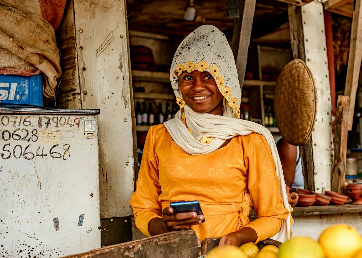 A stall owner in a yellow dress checking her phone